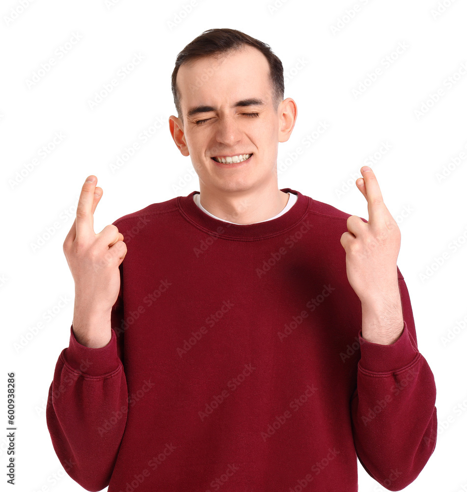 Young man crossing fingers on white background