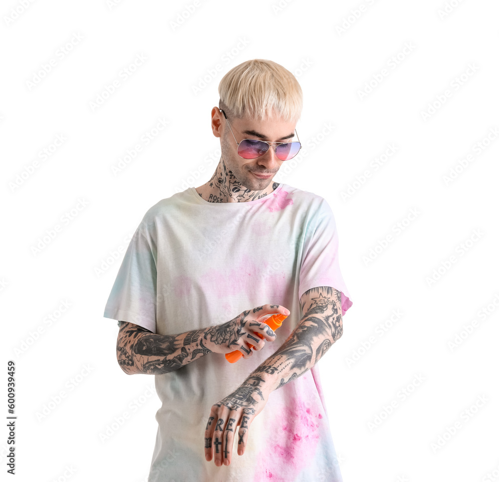 Tattooed man applying sunscreen cream against white background