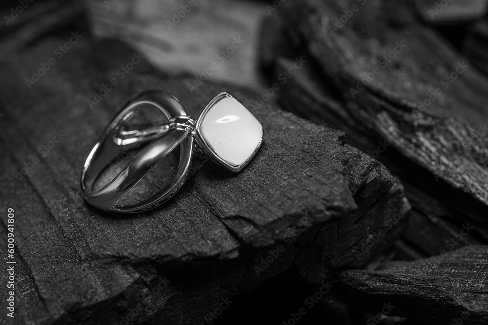 Silver ring on black charcoal, closeup