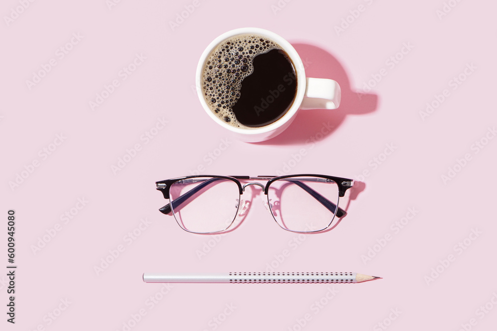 Modern black eyeglasses and cup of coffee on pale pink background