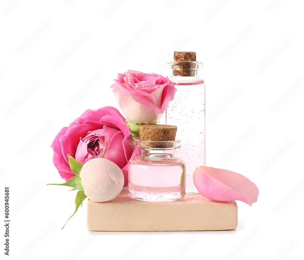 Bottles of cosmetic oil with rose extract and flowers on white background