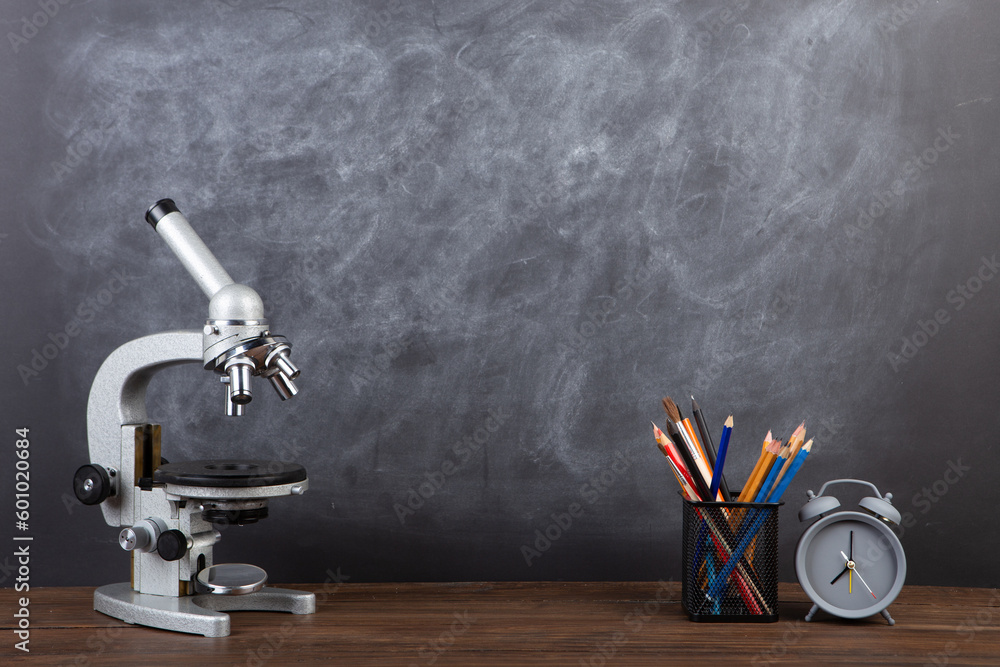 Back to school - books and microscope on the desk, Education concept. Blackboard background