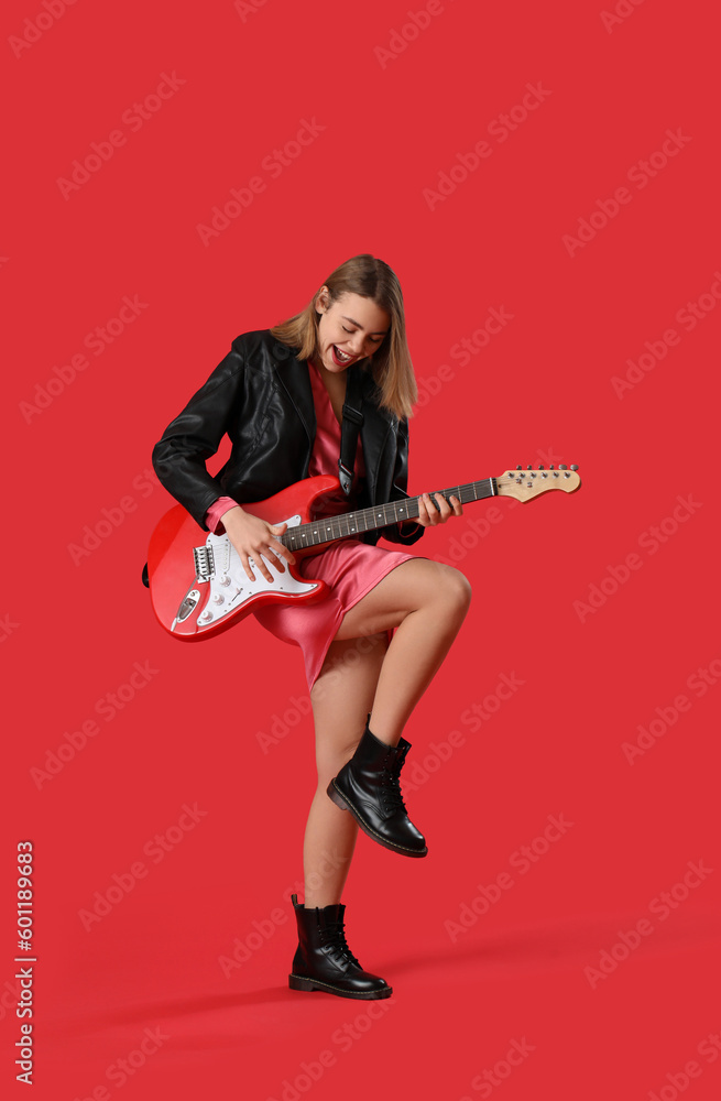 Young woman playing guitar on red background