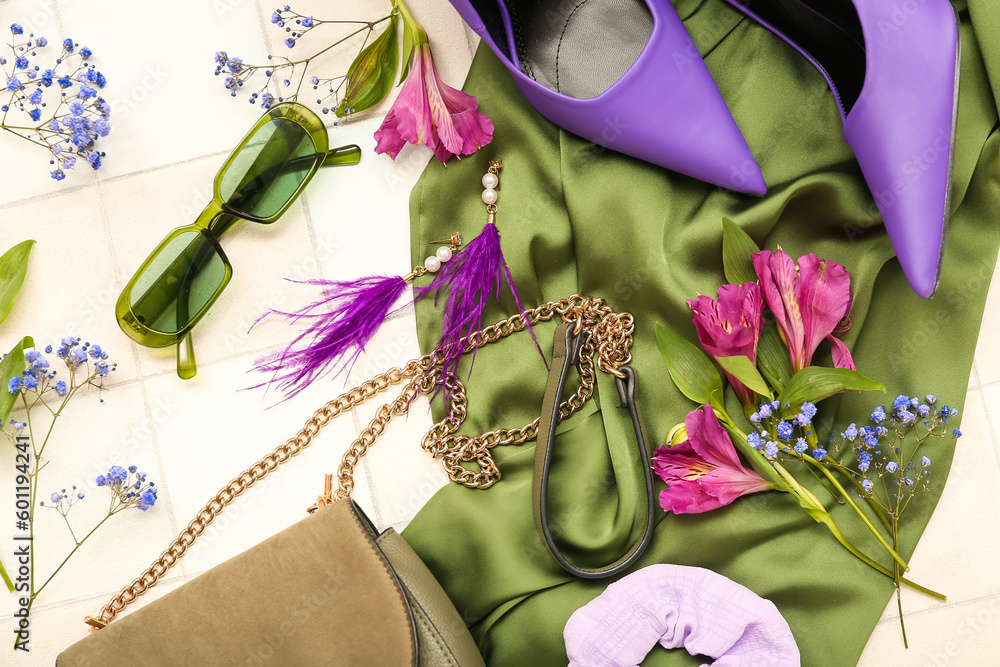 Composition with stylish female accessories, heels and flowers on light tile background, closeup