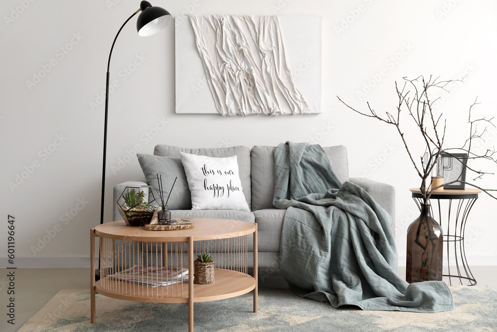 Interior of cozy living room with grey sofa and coffee table near white wall