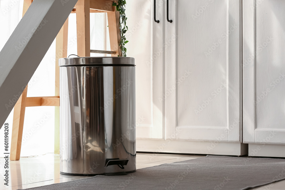 Metallic trash bin on floor in modern kitchen