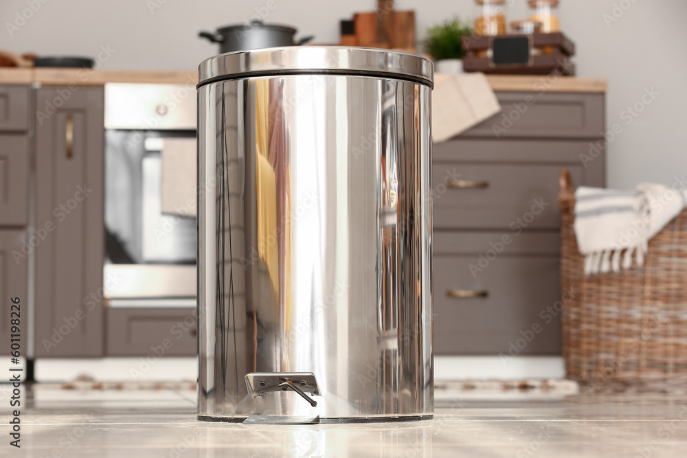 Metallic trash bin on floor in modern kitchen