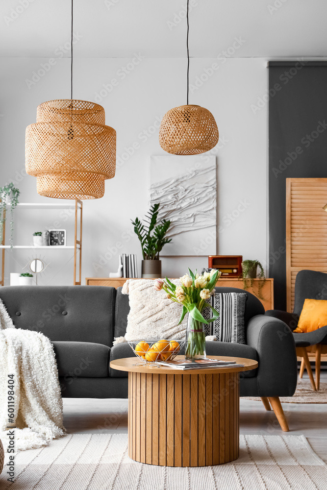 Vase with tulip flowers, lemons and magazines on coffee table in interior of living room