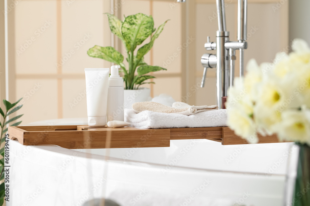 Tray with towels and cosmetic products in bathroom