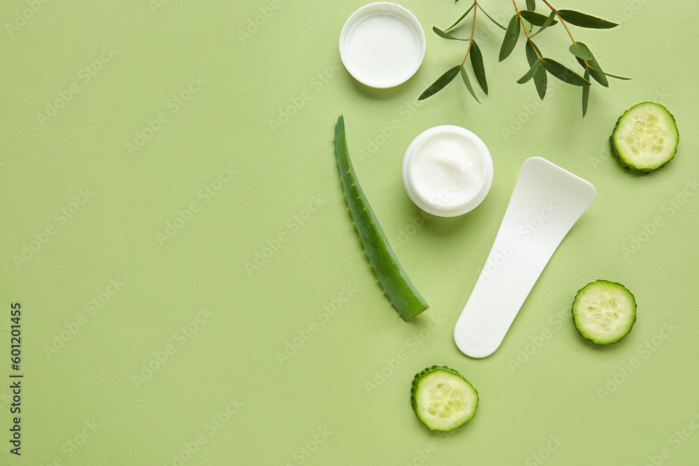 Composition with jar of natural cream, ingredients and spatula on color background