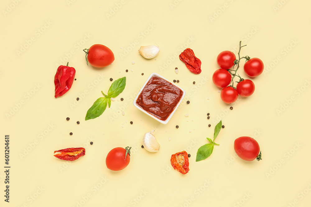 Bowl of delicious tomato sauce and ingredients on yellow background