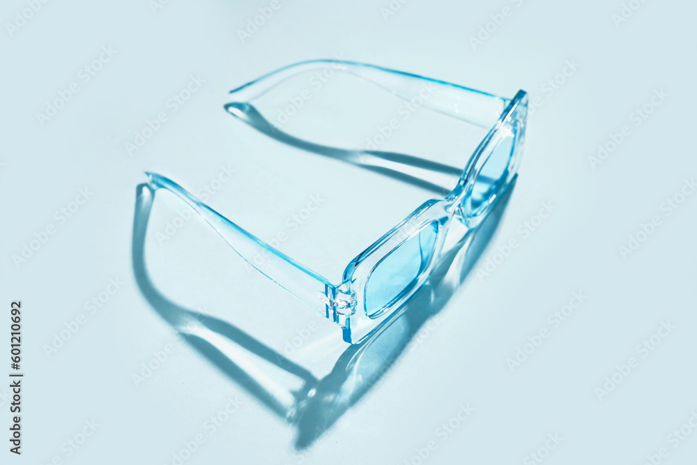 Stylish sunglasses on pale blue background