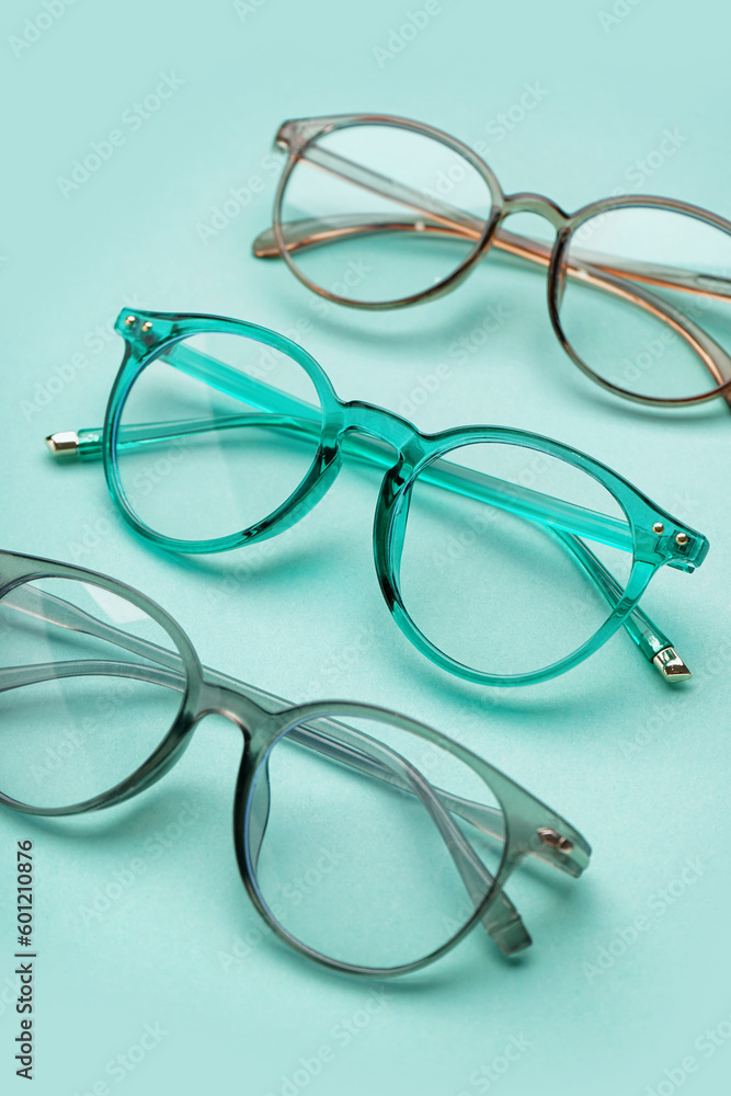 Different new eyeglasses on pale turquoise background