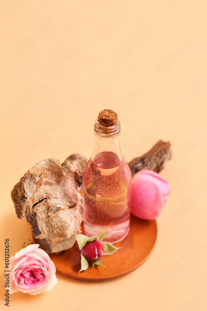 Bottle of cosmetic oil with rose extract and flowers on beige background