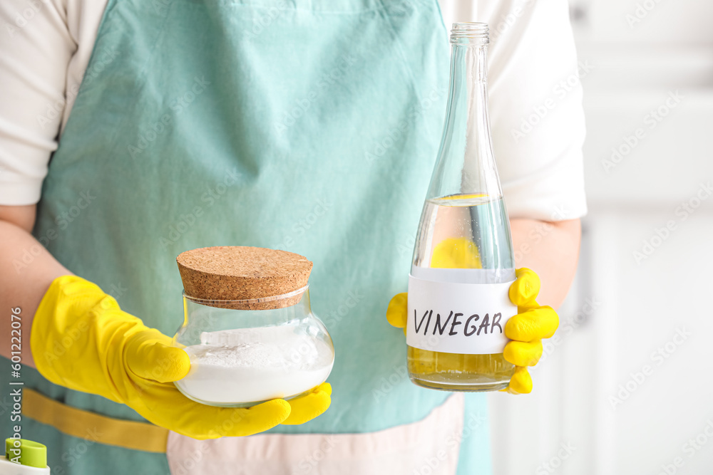 Woman with bottle of vinegar and baking soda, closeup