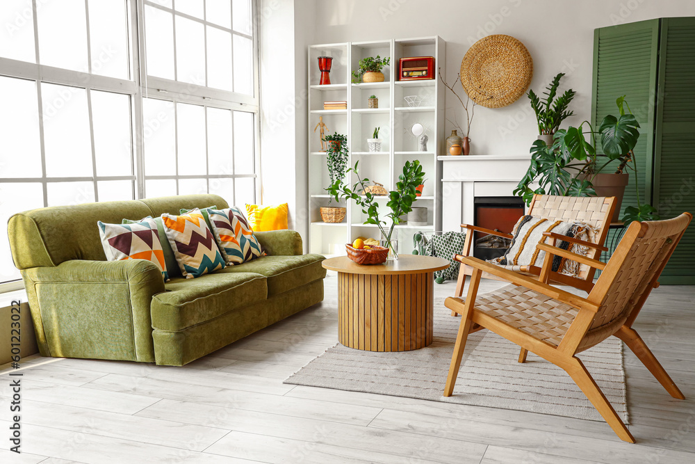 Interior of bright living room with cozy sofa, armchairs and coffee table near big window