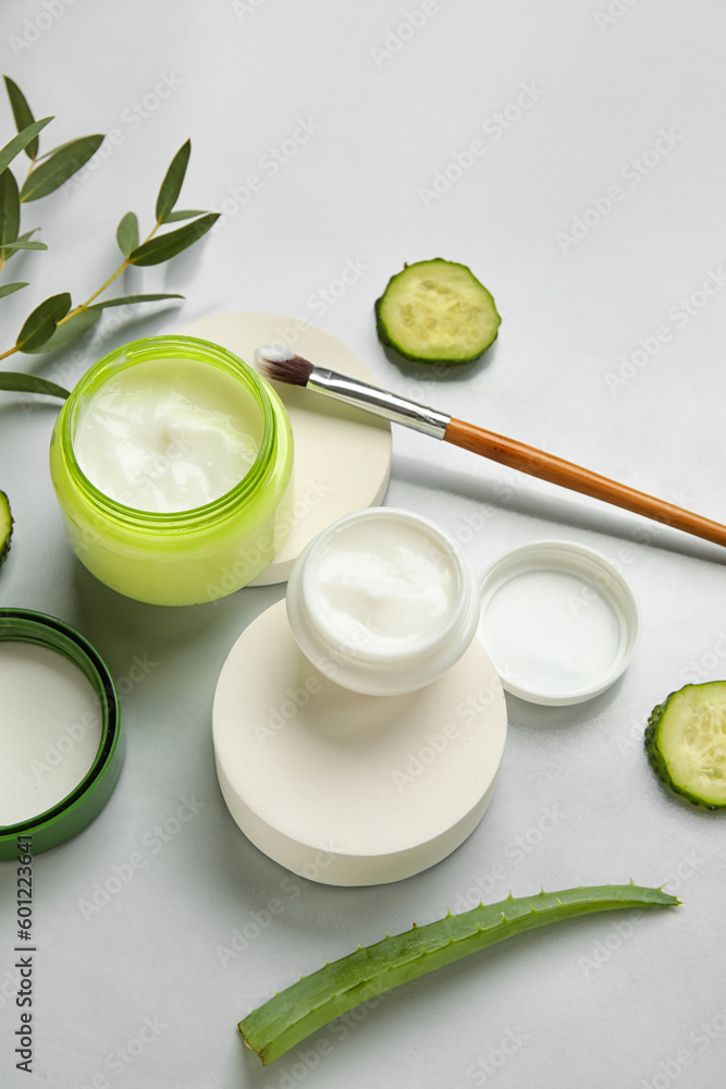 Composition with jars of natural cream and ingredients on light background