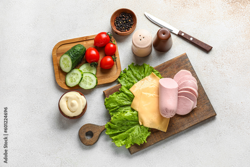 Boards with tasty boiled sausage, cheese and vegetables on light background