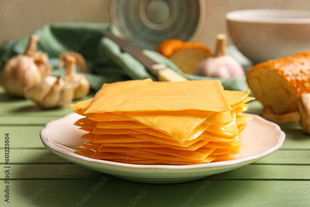 Plate with slices of tasty processed cheese on table