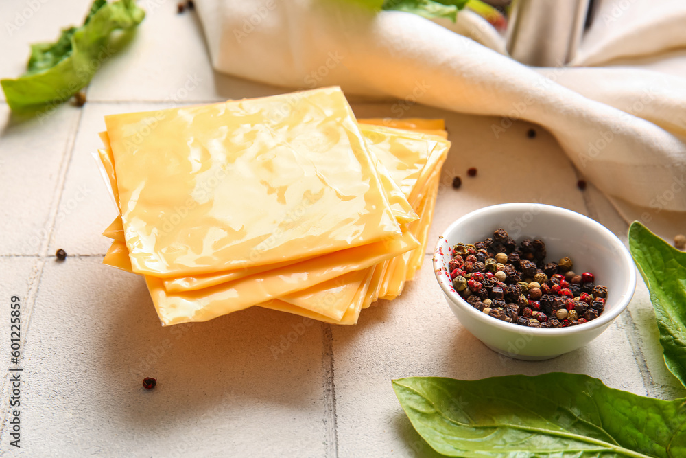 Slices of tasty processed cheese on white tile background