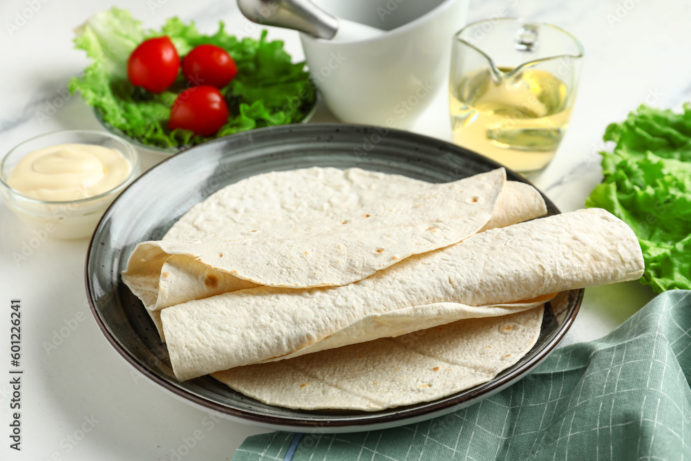 Plate with fresh lavash on light background