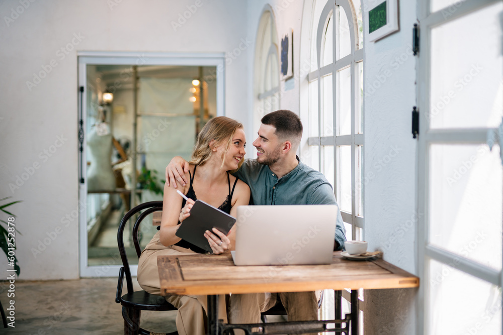 Loving young caucasian couple using laptop together while sitting in chair at home. Concept of coupl