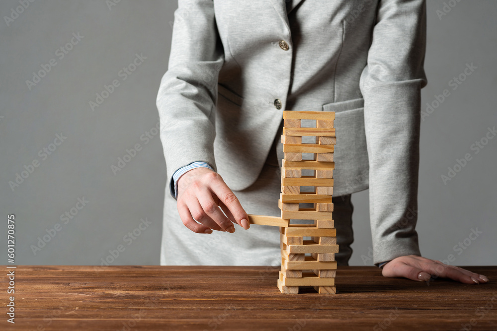 Businesswoman removing wooden block from tower