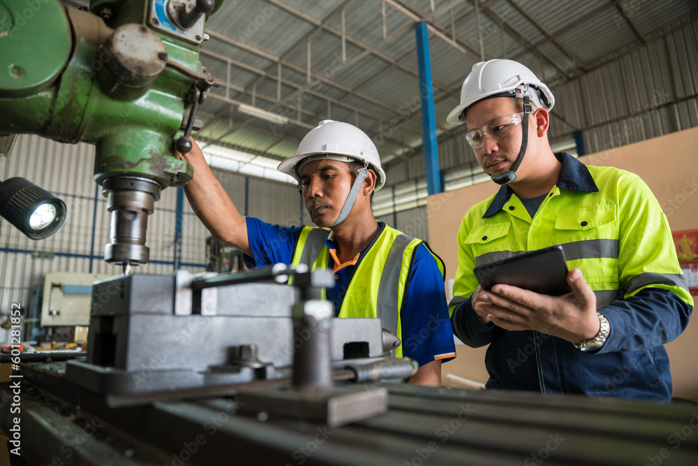 Asian engineers working with worker wearing safety goggles working at lathe. Safety first concept.