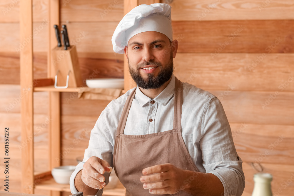 Male baker cooking at table in kitchen