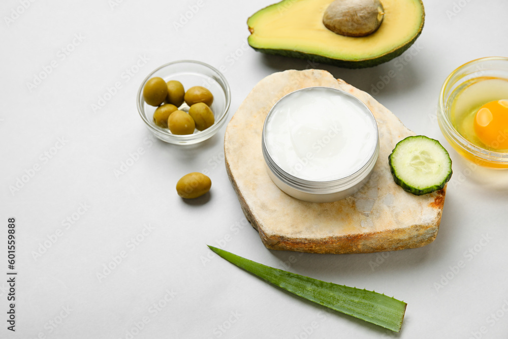 Composition with jar of natural cream and ingredients on light background