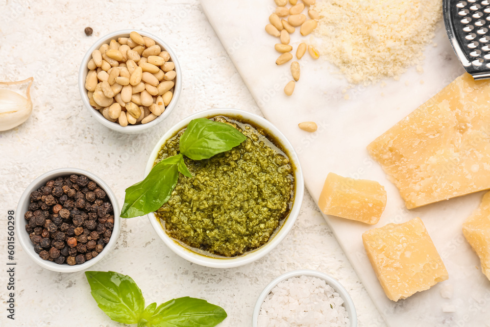 Composition with bowl of pesto sauce and ingredients on white table