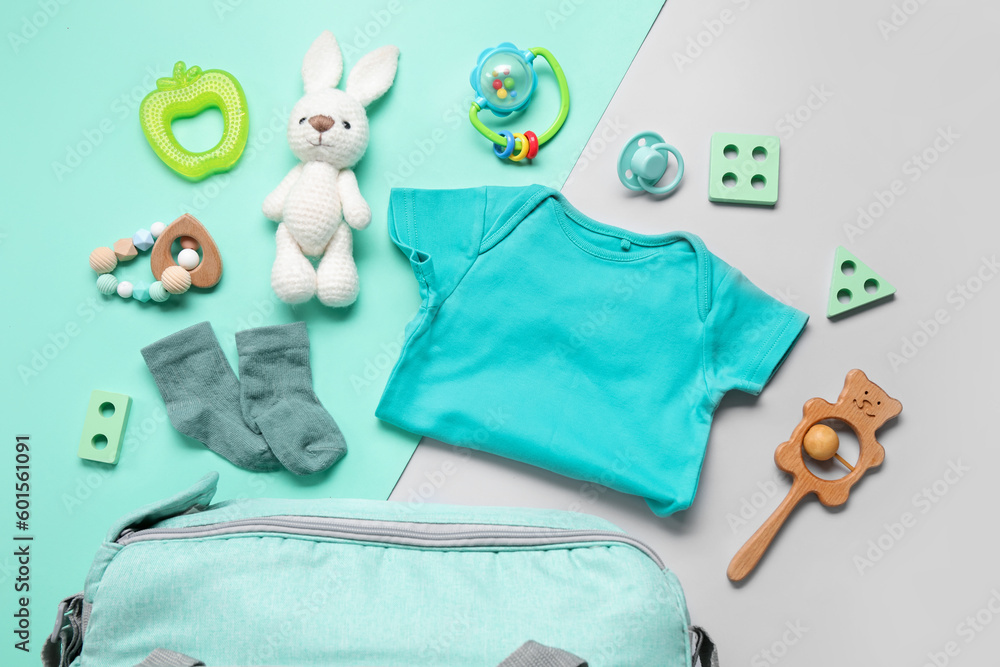 Composition with baby clothes and toys on turquoise background