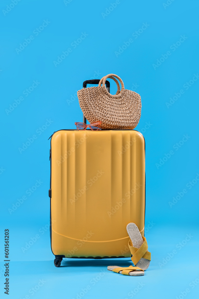 Suitcase with beach accessories on blue background