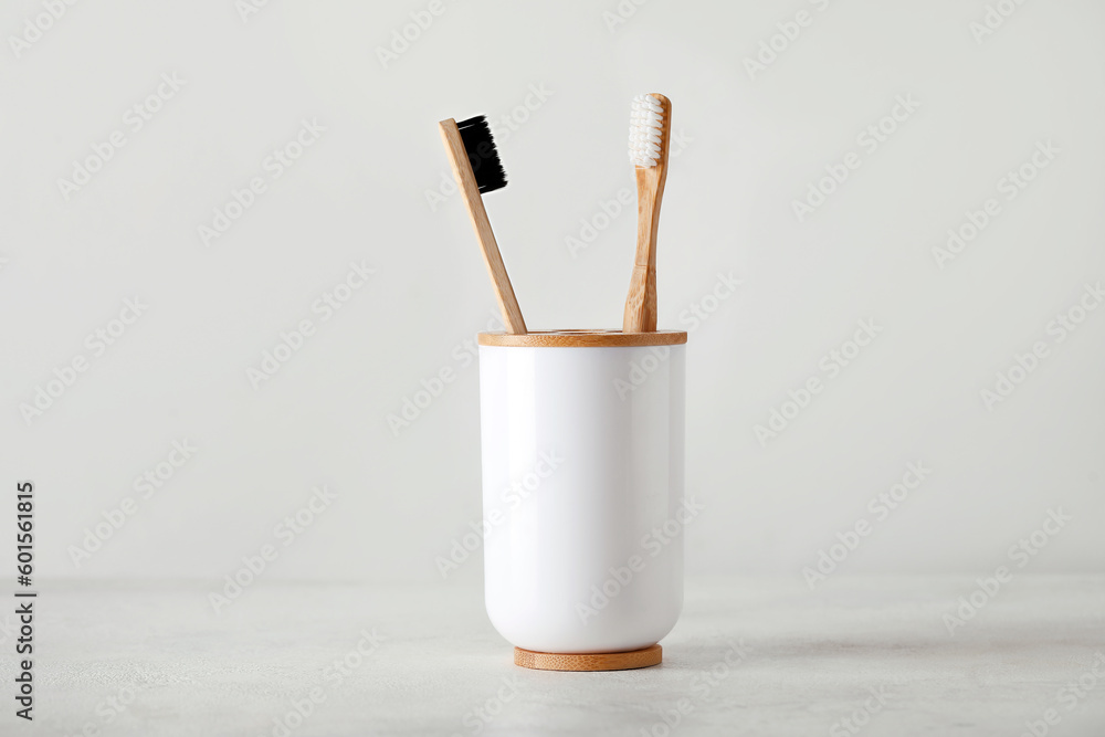 Holder with bamboo toothbrushes on white table