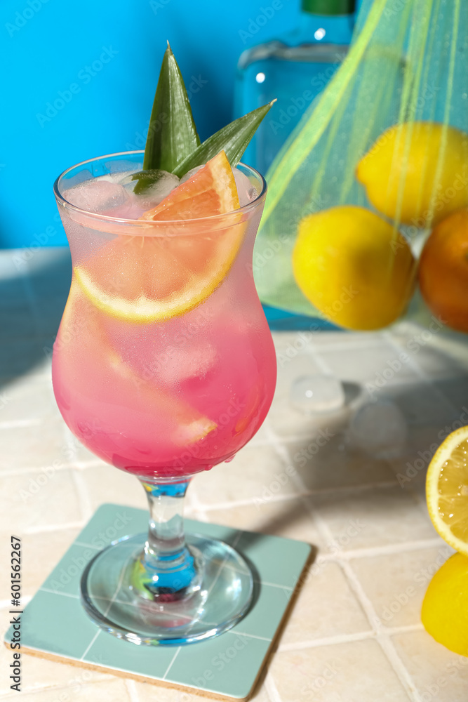 Fresh summer cocktail with grapefruit on tile table near blue wall