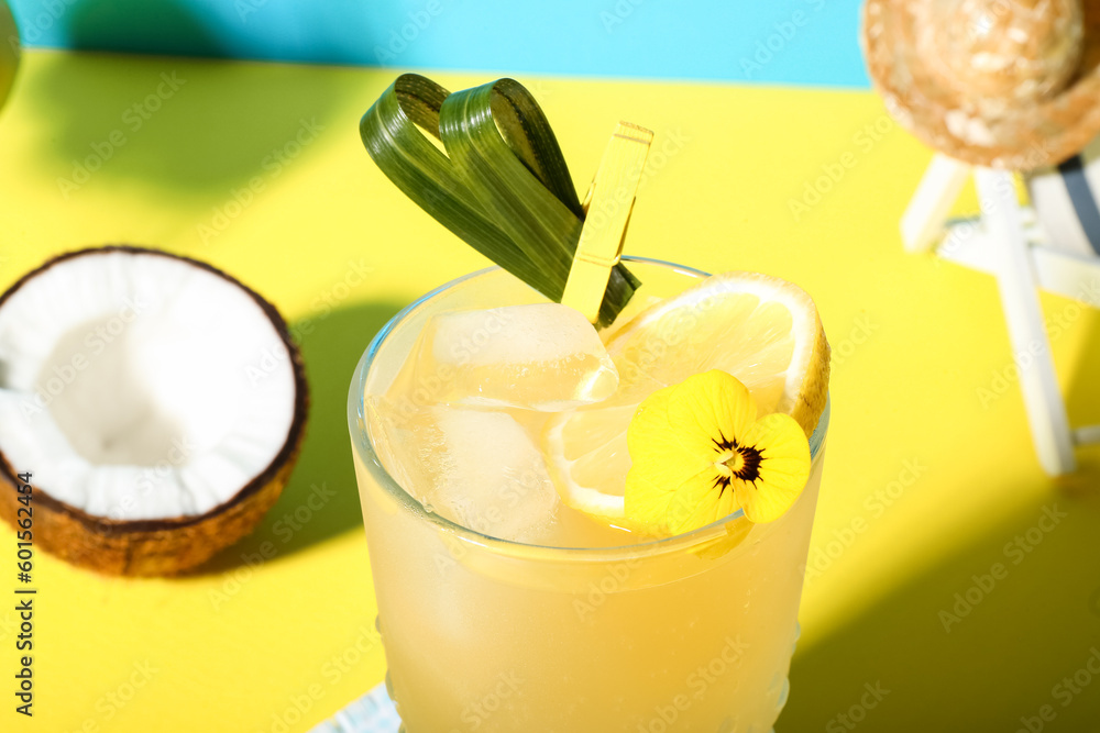 Fresh summer cocktail with lemon and flower on yellow table near blue wall