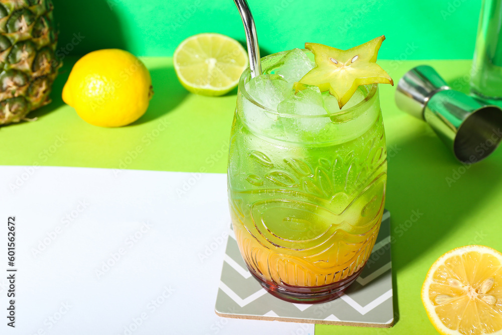 Fresh summer cocktail with carambola and straw on green table