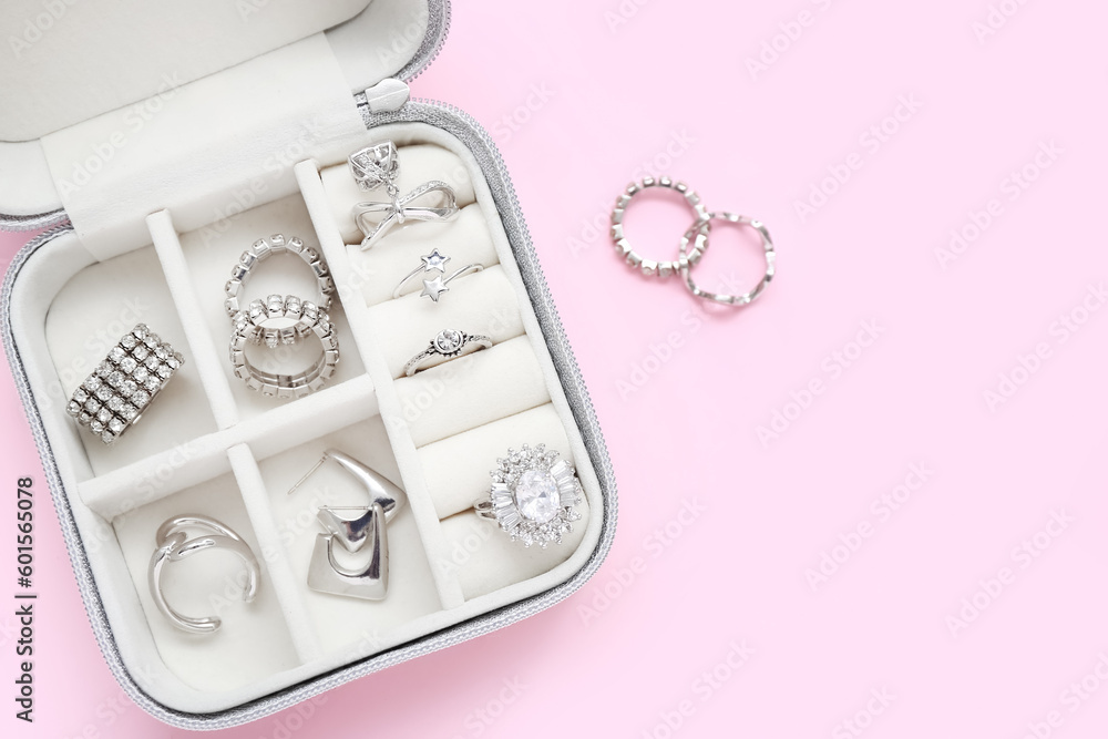 Opened organizer with stylish silver rings on pink background