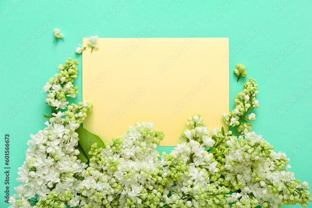 Yellow blank card and lilac flowers on turquoise background