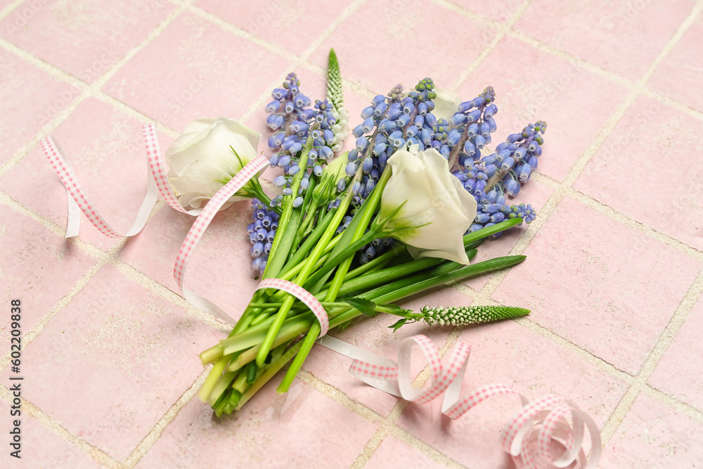 Bouquet of beautiful Muscari and eustoma flowers on pink tiled background