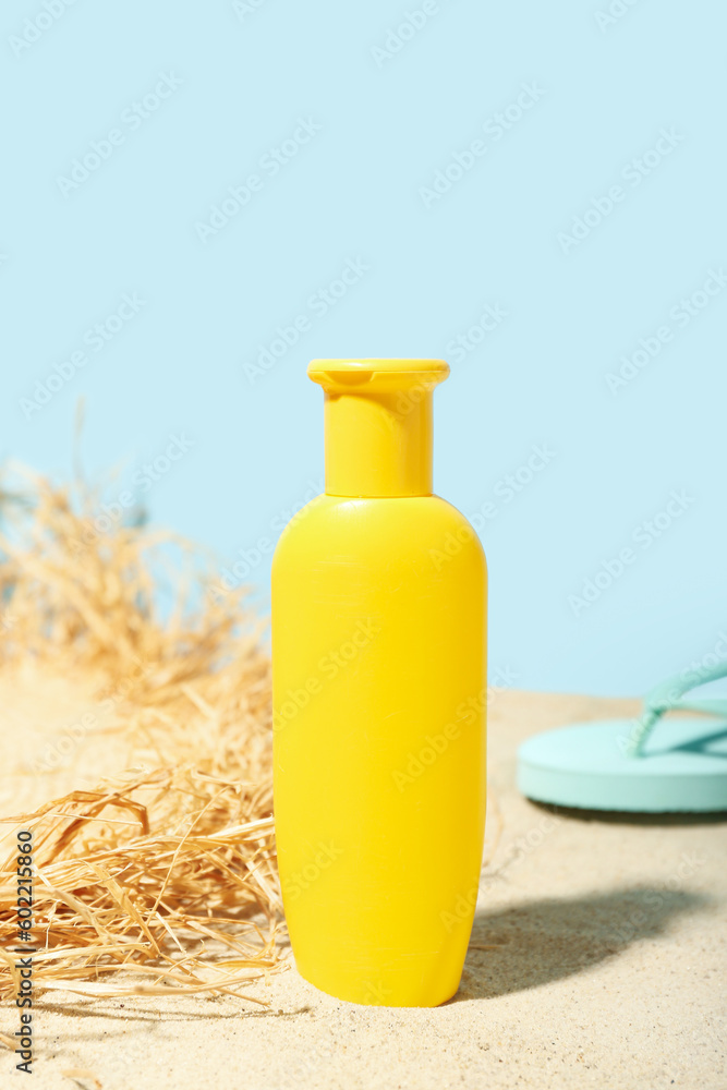 Creative composition with sunscreen cream, summer hat and flip flops on sand