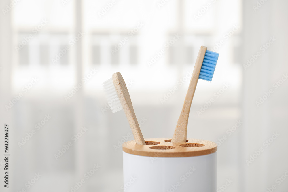 Holder with bamboo toothbrushes in room, closeup