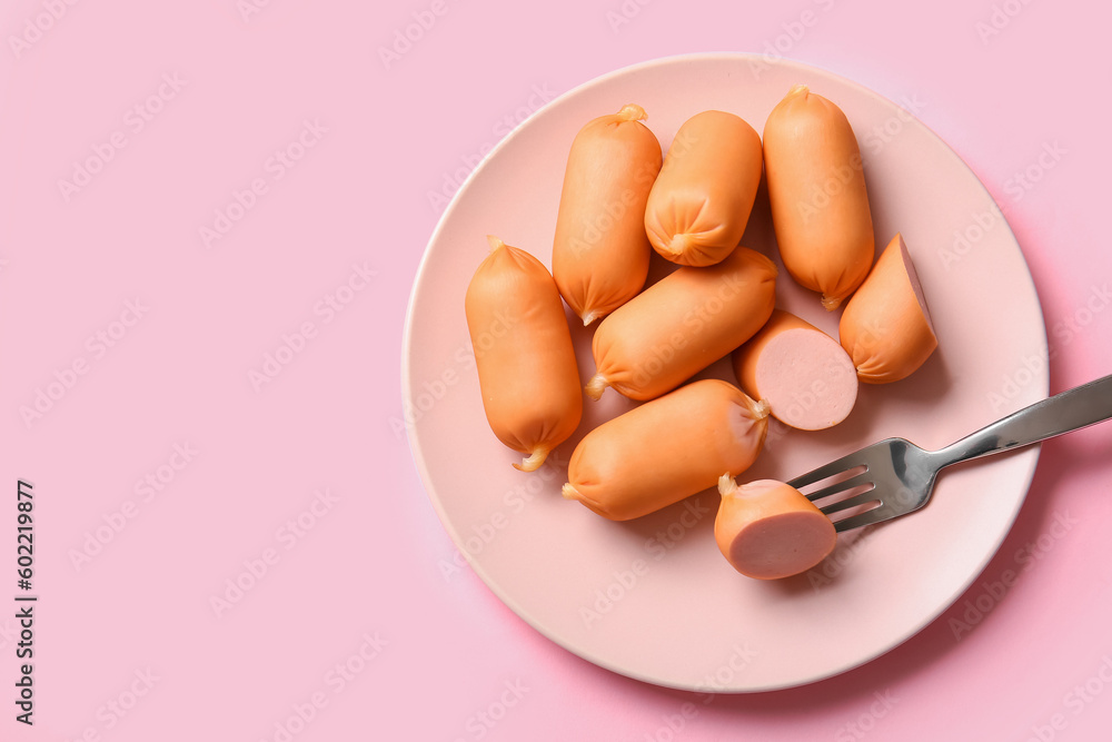 Plate of tasty boiled sausages on pink background