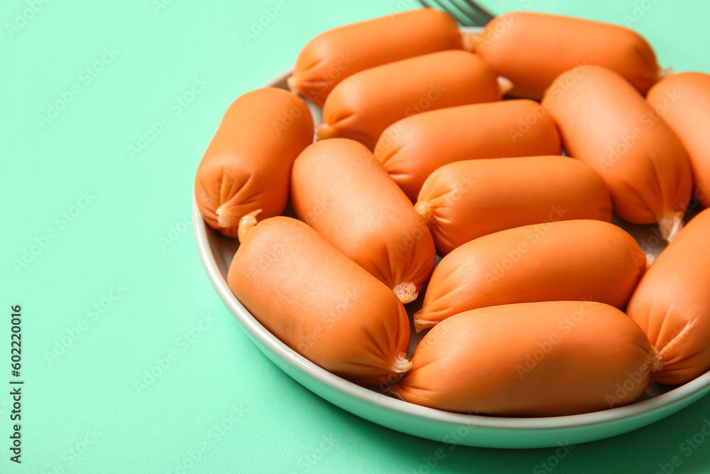 Plate of tasty boiled sausages on turquoise background