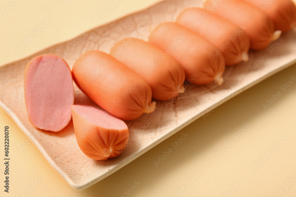 Plate of tasty boiled sausages on beige background