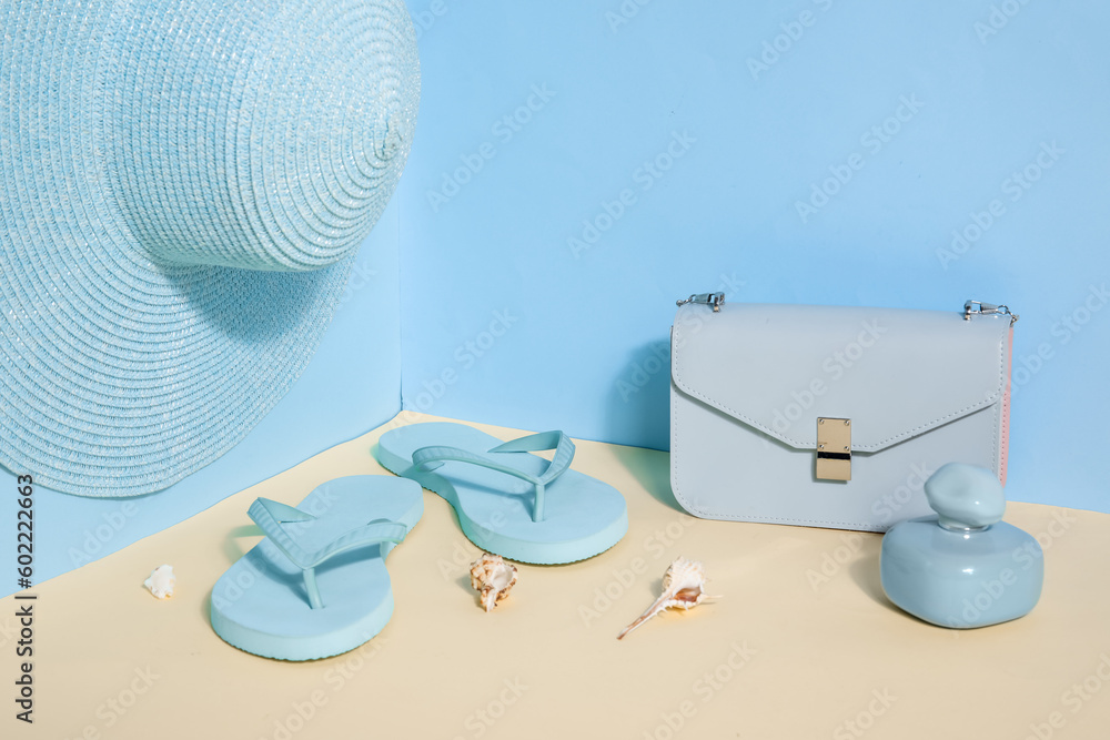 Flip flops with bag and wicker hat near blue wall