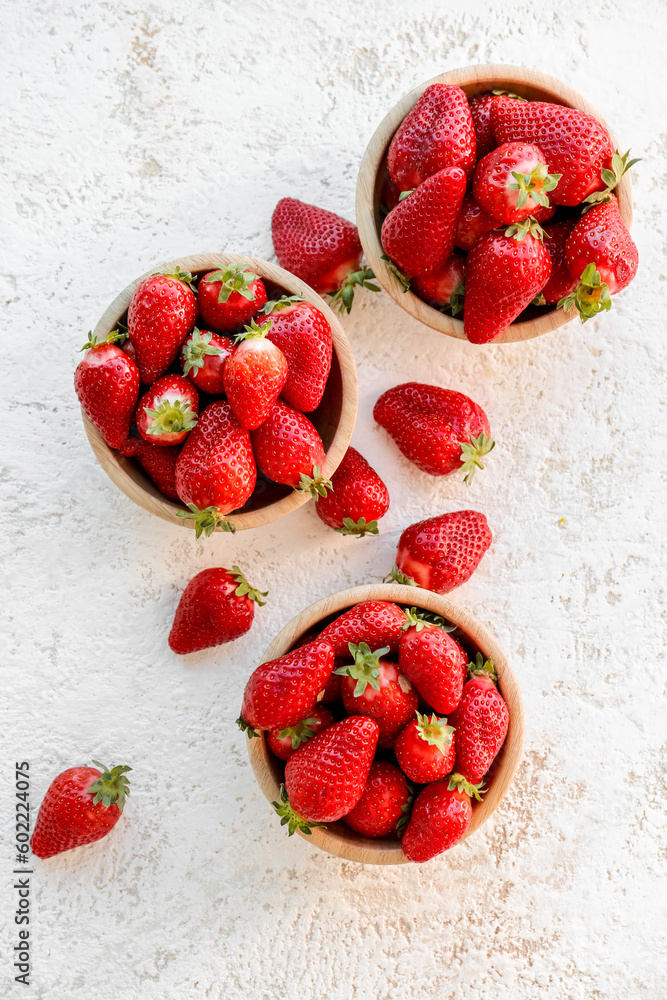 Bowls with fresh strawberries on white background