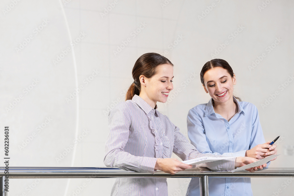 two young women discuss documents