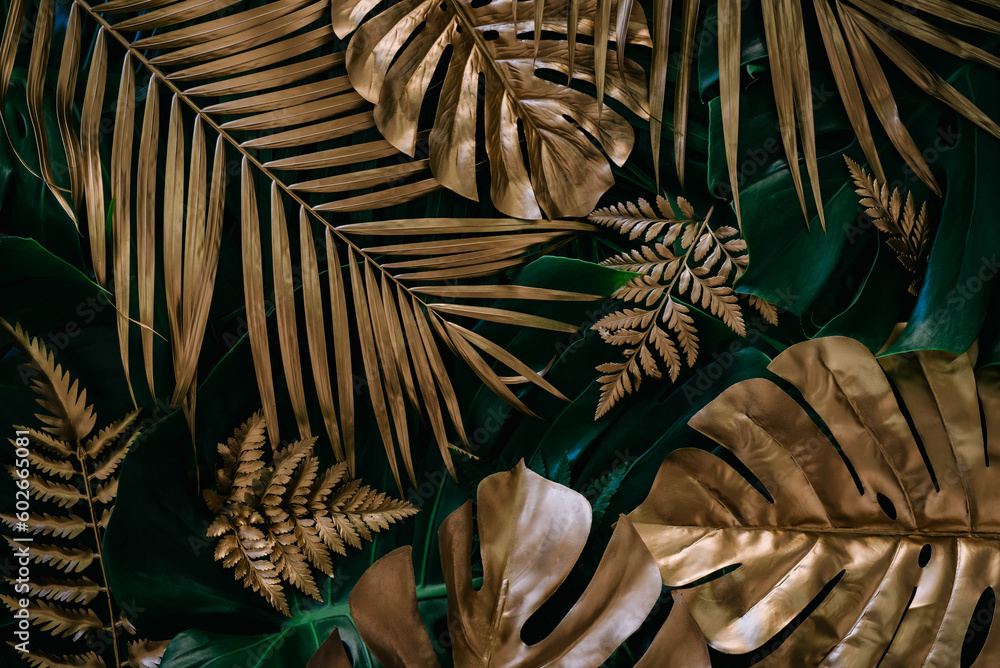 Creative nature background. Gold and green tropical Monstera and palm leaves. Minimal summer abstrac