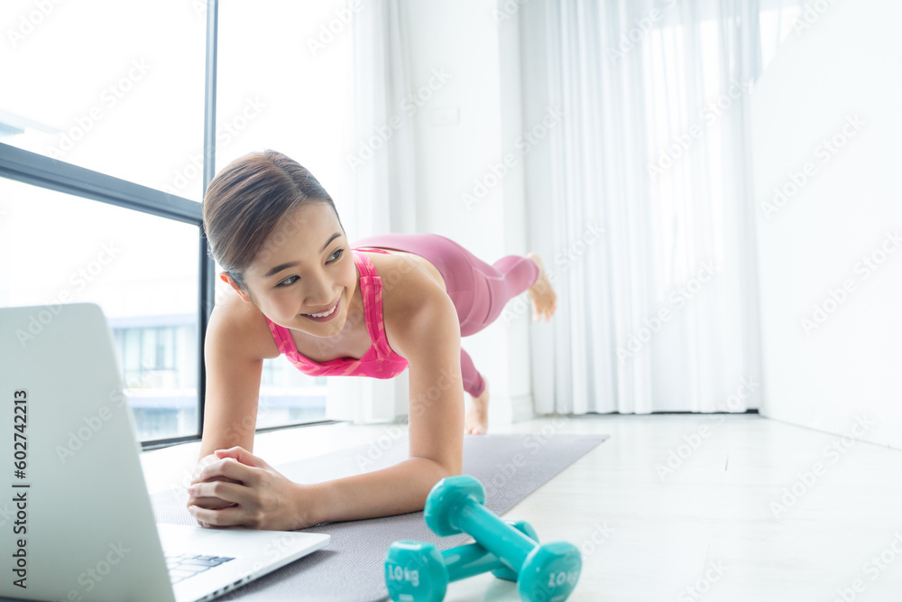 Asian Woman training fitness Plank pose at home watch online tutorial on laptop